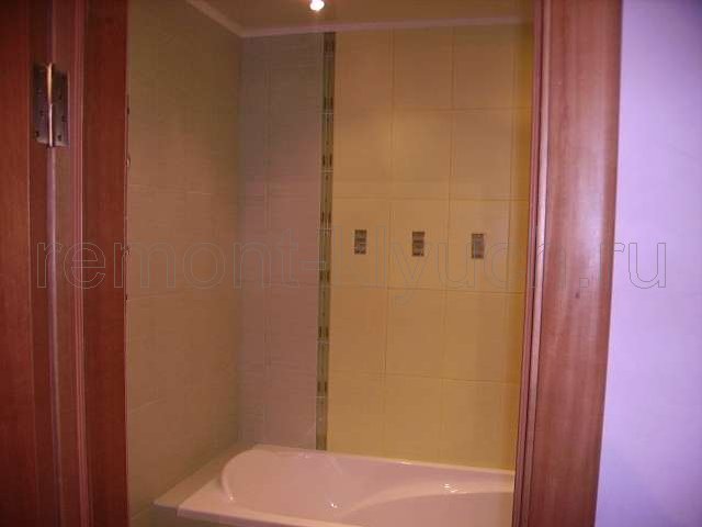 Облицовка стен ванной комнаты керамическими плитками с декором и устройством бордюра, выложенного по вертикали, монтаж дверного блока